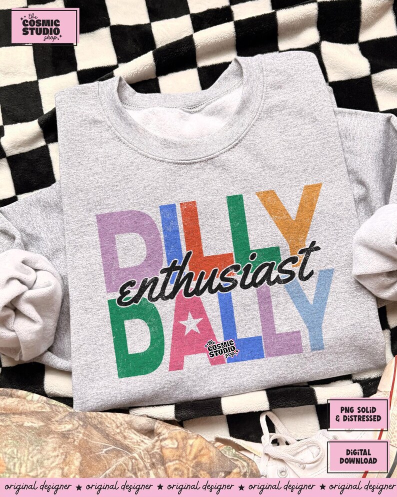 May include: A heather gray sweatshirt with the text "DILLY enthusiast DALLY" in colorful block letters. The design includes a star and the words "the COSMIC STUDIO shop". The sweatshirt is a digital download.