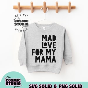 Puede incluir: Una sudadera gris claro con el texto "MAD LOVE FOR MY MAMA" en letras negras en negrita. La sudadera est&aacute; colgada de una percha blanca sobre un fondo blanco. La imagen tambi&eacute;n incluye el texto "the COSMIC STUDIO shop. DESIGNER" y "SVG SOLID & PNG SOLID".