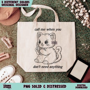 May include: Cream-colored tote bag with a black and white illustration of a cat holding a phone. The text "call me when you don't need anything" is above and below the cat. The words "3 DIFFERENT COLORS ORIGINAL DESIGNER" are at the top.