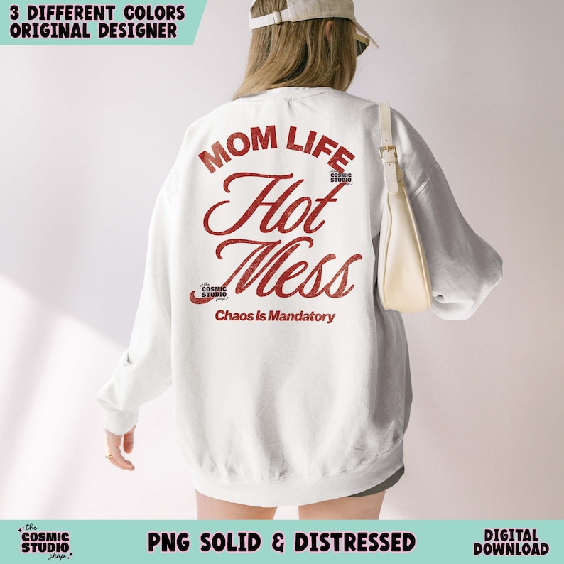 May include: White sweatshirt with the text "MOM LIFE Hot Mess Chaos Is Mandatory" in red. The sweatshirt also has the text "the COSMIC STUDIO shop." The image also includes the text "3 DIFFERENT COLORS ORIGINAL DESIGNER" and "PNG SOLID & DISTRESSED DIGITAL DOWNLOAD."