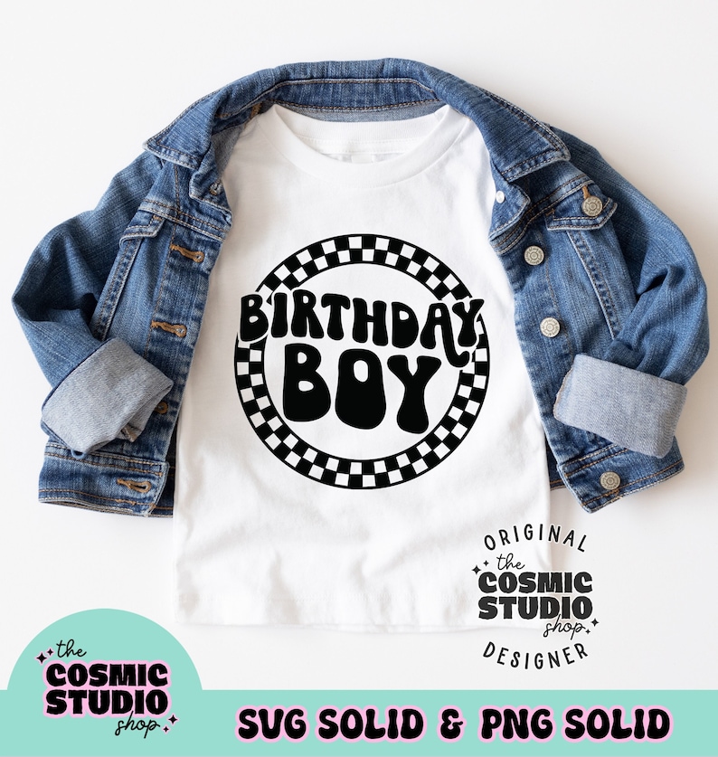 May include: A white t-shirt with the words "BIRTHDAY BOY" in a black, retro font, encircled by a black and white checkered pattern. The shirt is displayed on top of a denim jacket.
