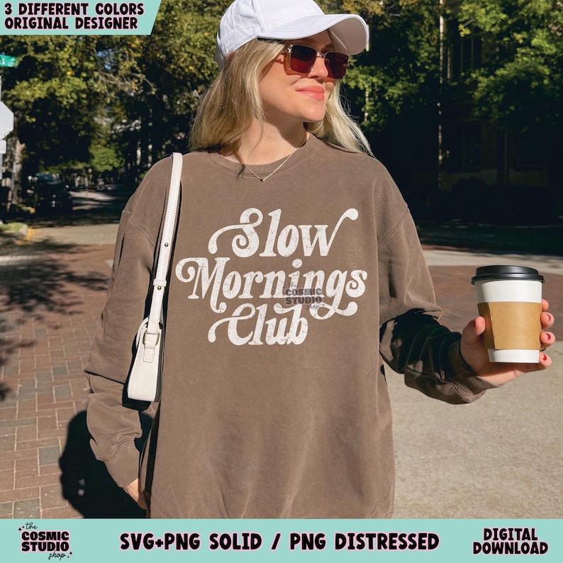 May include: A brown sweatshirt with the text "Slow Mornings Club" in white. The sweatshirt is being worn by a person with a white baseball cap and sunglasses.