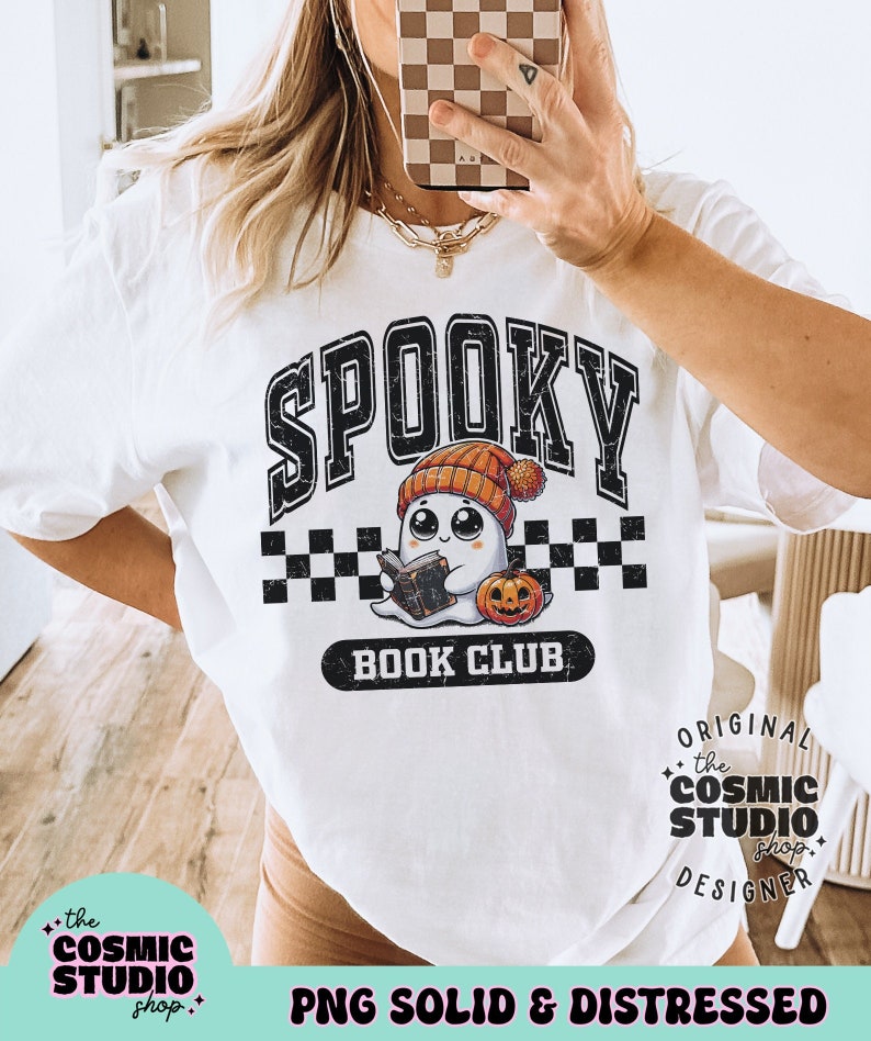 May include: A white t-shirt featuring a black and white graphic of a ghost wearing a hat and holding a book. The text "Spooky Book Club" is printed below the ghost. The text "the COSMIC STUDIO shop" is printed in the bottom left corner of the image. The text "ORIGINAL the COSMIC STUDIO shop DESIGNER" is printed in the bottom right corner of the image. The text "PNG SOLID & DISTRESSED" is printed at the bottom centre of the image.