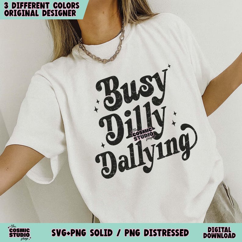 May include: A white t-shirt with the text "Busy Dilly Dallying" in a black, retro font. The shirt also features the text "the COSMIC STUDIO shop." and the phrases "3 DIFFERENT COLORS ORIGINAL DESIGNER" and "SVG+PNG SOLID / PNG DISTRESSED DIGITAL DOWNLOAD".