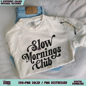 May include: A white t-shirt with black text that reads "Slow Mornings Club".