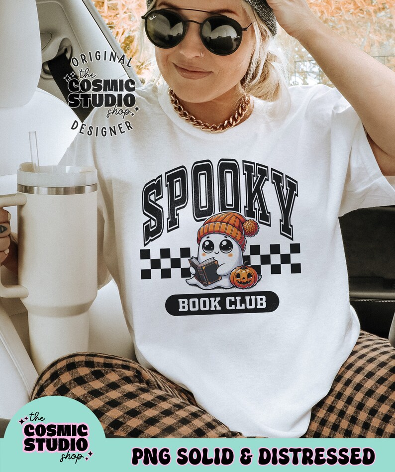 May include: White t-shirt featuring a black and white graphic of a ghost wearing a hat and holding a book. The graphic reads "Spooky Book Club".