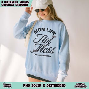 May include: A light blue sweatshirt with the words "MOM LIFE Hot Mess" in a black script. The phrase "Chaos Is Mandatory" is below the main text. The sweatshirt is a digital download.