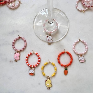 May include: Set of six colorful beaded wine glass charms with various Easter-themed charms, including a chick, bunny, and carrot.