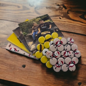 May include: A set of four coasters featuring a photograph of two people sitting on a bench. The coasters are made of cork and have a yellow and white design. The coasters are surrounded by a circle of small, round, white coasters with a red and white design.