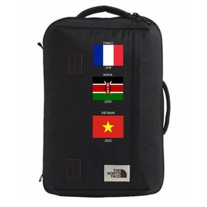 May include: Black travel backpack with multiple handles and straps. Features flags of France, Kenya, and Vietnam with corresponding years. The North Face logo is visible on the bottom.