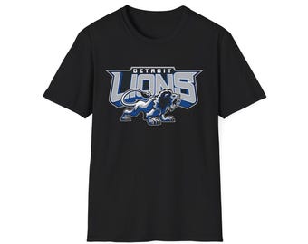 Könnte beinhalten: Schwarzes T-Shirt mit dem Logo der Detroit Lions. Das Logo zeigt das Wort "LIONS" in einer stilisierten Schriftart mit einer blau-weißen Löwengrafik. Das Wort "DETROIT" steht über dem Logo.