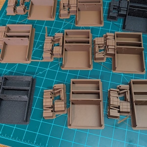 May include: A collection of brown and black miniature wooden storage boxes with shelves and drawers. The boxes are arranged on a green cutting mat with a ruler.