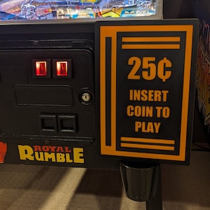 May include: A black and orange arcade game sign with the text "25C INSERT COIN TO PLAY".