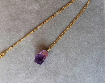 May include: A gold chain necklace with a purple amethyst crystal pendant.