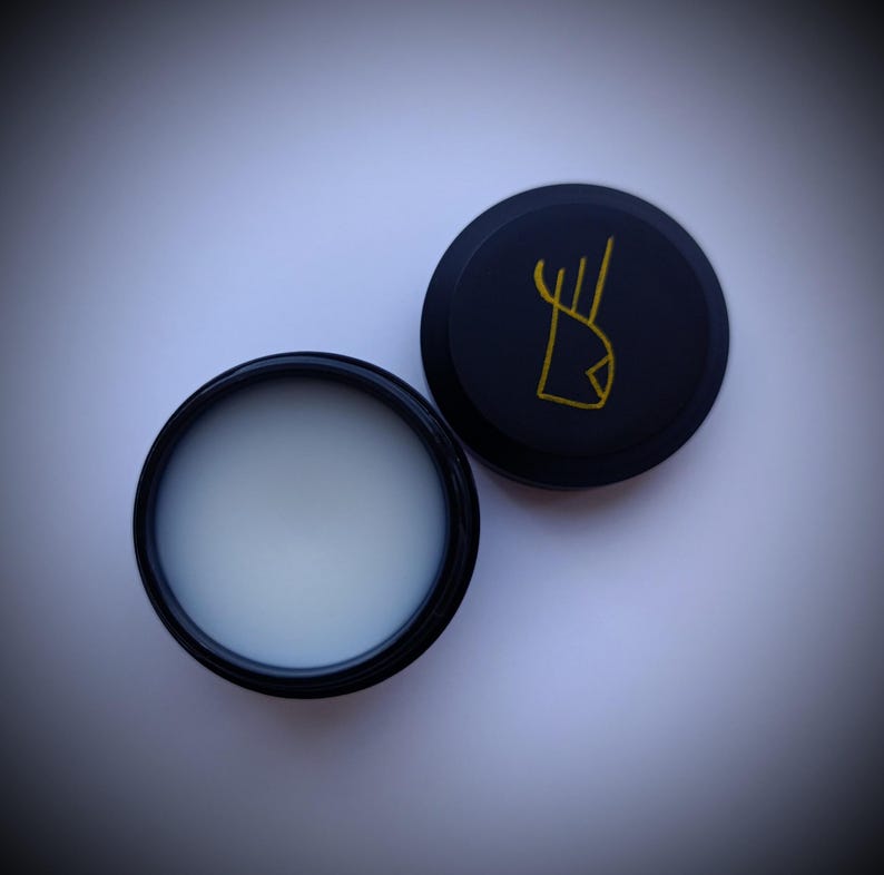 K&ouml;nnte beinhalten: Ein schwarzer Beh&auml;lter mit einer wei&szlig;en Creme darin. Der Deckel ist schwarz mit einem goldenen Logo eines stilisierten Hirschkopfes.