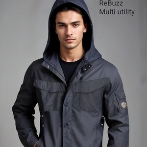 May include: A charcoal gray multi-utility jacket with a hood. The jacket features two front pockets, a chest pocket, and a small pocket on the sleeve. The jacket has a button-up front and a dark gray hood. The text "ReBuzz Multi-utility" is visible.