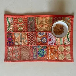 Könnte beinhalten: Ein roter Patchwork-Tischläufer mit bunter Stickerei und einer kleinen weißen Schale gefüllt mit Mandeln.