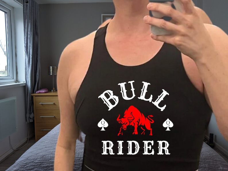 May include: Black tank top with a white graphic of a red bull and the text "BULL RIDER" with two spade symbols.