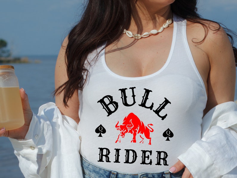 May include: White tank top with a black and red graphic of a bull and the text "BULL RIDER" with two black spade symbols.