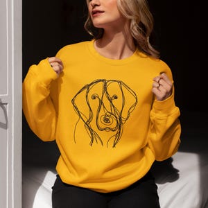 May include: A yellow sweatshirt with a black line drawing of a dog's head on the front.