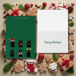 A Christmas-themed greeting card featuring six black cat illustrations. Each cat is depicted in a different festive outfit, including a Santa hat, bow, garland, and reindeer antlers.  An open card is sitting next to it with words, "Happy Holidays" in green script.