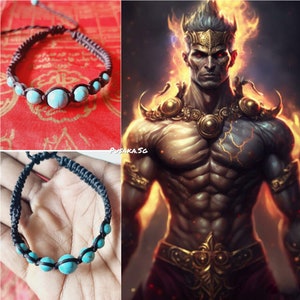 May include: A black braided bracelet with turquoise beads. The bracelet is on a hand and a red background.