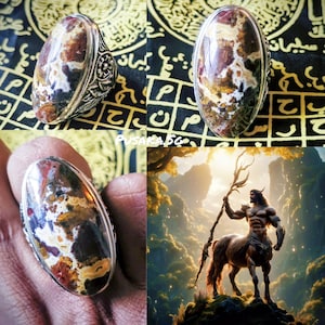 Puede incluir: Anillo ovalado con banda plateada y piedra con patrones marrones, blancos y amarillos. La imagen también incluye una ilustración digital de un centauro sosteniendo un bastón.