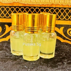 May include: Four small glass bottles with gold lids and a clear liquid inside. The bottles are sitting on a black and gold patterned surface. The text "Pusaka.Sg" is visible on the surface.