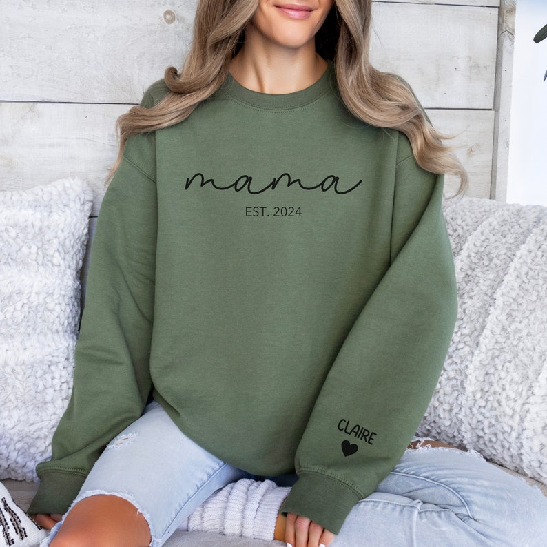a woman sitting on a couch wearing a green sweatshirt
