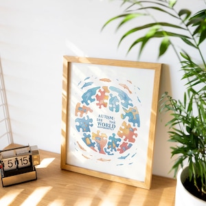 Può includere: Una stampa incorniciata con sfondo bianco e un'illustrazione colorata di pezzi di puzzle che formano un cerchio. Il testo "Autismo: Vedere il mondo in modo diverso" è scritto al centro del cerchio.