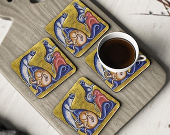 May include: Set of four square coasters featuring a medieval-style illustration of two blue and white cats with red and gold accents. The cats are depicted in a playful pose, with one cat holding a round object in its paws. The coasters are made of a durable material and are perfect for protecting your furniture from spills and scratches.