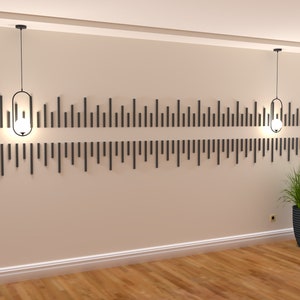 May include: Two black pendant lights with clear glass shades hang from the ceiling in a room with beige walls and a wood floor. A black decorative wall panel with vertical lines is mounted on the wall behind the lights.