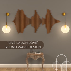 Op de afbeelding: Een houten geluidsgolf wandkunst met de tekst "LIVE LAUGH LOVE" en "SOUND WAVE DESIGN" eronder. Twee gouden hanglampen met heldere glazen lampenkappen hangen aan weerszijden van de kunst. Een kleine houten tafel met een tijdschrift en een vaas met bloemen staat voor de kunst.