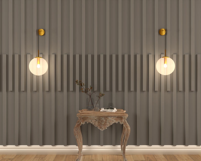 May include: Two gold wall sconces with frosted glass globe shades hang on a gray wall with vertical wood paneling. A small wooden table with ornate legs sits in front of the sconces.