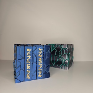 May include: Two blue and black geometric boxes with a gold inscription on the blue box. The inscription reads "aufrk & zuf".