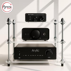 May include: A three-tiered audio component shelf with clear acrylic shelves and metal supports. The shelf holds three black audio devices, including a "Fost Audio" amplifier and an "Arylic" streamer. The shelf is labeled "Nyenius Studio".