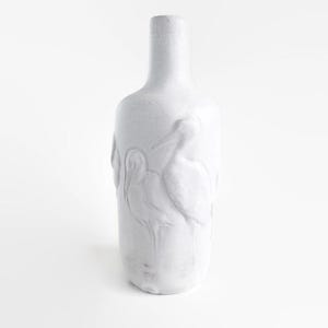 May include: A white ceramic vase with a slender neck and a rounded body. The vase features a raised relief design of several birds. The overall aesthetic is minimalist and elegant, suitable for home decor.