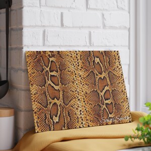 Op de afbeelding: Een rechthoekige snijplank met een slangenprint in bruine en bruine tinten. De plank heeft een glanzende afwerking en de tekst "Savor Smith" is zichtbaar in de rechter benedenhoek.