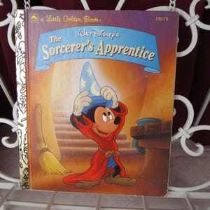 May include: A Little Golden Book cover featuring Mickey Mouse as Sorcerer's Apprentice. Mickey is wearing a blue pointed hat and a red robe. The book title is "The Sorcerer's Apprentice" with a gold background.