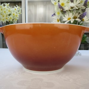 Peut inclure: Un grand bol à mélanger orange avec un bord blanc. Le bol est en céramique et présente un dégradé de couleur, passant d'un orange clair à un orange plus foncé.
