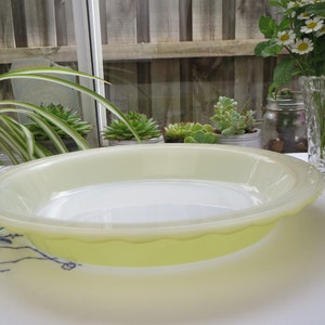 Może przedstawiać: Żółta forma do ciasta z falistym brzegiem. Forma jest wykonana ze szkła i stoi na białym obrusie.