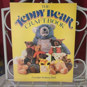 May include: A yellow book titled "The Teddy Bear Craft Book" with a collection of teddy bears on the cover. The book features a large blue teddy bear and several smaller bears in various colors and styles. The author's name, Carolyn Vosburg Hall, is also visible.