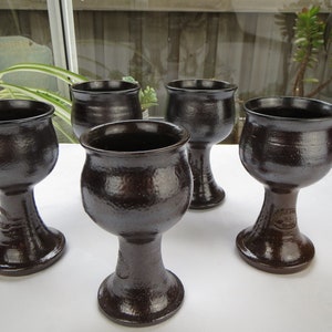 Peut inclure: Ensemble de quatre gobelets en céramique brun foncé avec une surface texturée. Chaque gobelet a un bol rond et une tige haute et mince.
