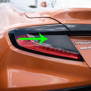 May include: A close-up of the rear taillight of a Subaru car. The taillight is a combination of red and clear lenses. The Subaru logo and "AWD" are visible on the rear of the car.