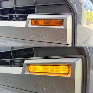 Könnte beinhalten: Nahaufnahme des Fahrzeugfronts, die ein rechteckiges, bernsteinfarbenes Seitenmarkierungslicht zeigt. Das Licht ist in das Design des Stoßfängers integriert, mit einem dunkelgrauen Kühlergrill und Zierleisten. Das Licht ist im oberen Bild ausgeschaltet und im unteren Bild eingeschaltet.