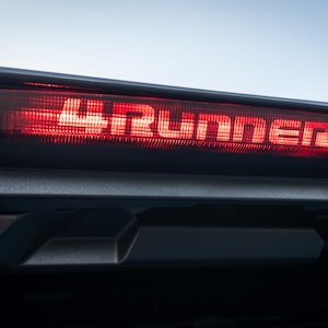 Puede incluir: Una luz trasera roja con la palabra "4RUNNER" iluminada en blanco.