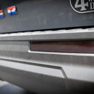 Puede incluir: Primer plano de un parachoques gris de vehículo con un reflector rectangular rojo oscuro. La palabra "RANGER" es visible en letras rojas, blancas y azules. También es visible una pegatina con el texto "4 WHEEL DRIVE".