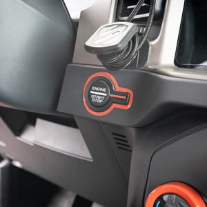 May include: Close-up of a black car interior with a red engine start/stop button. The button has the words "Engine Start Stop" printed on it.