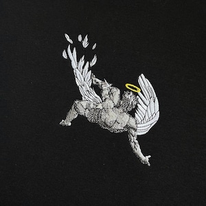 Op de afbeelding: Zwarte hoodie met een wit geborduurd beeld van een engel met vleugels die uit de lucht valt. De engel heeft een halo boven zijn hoofd.