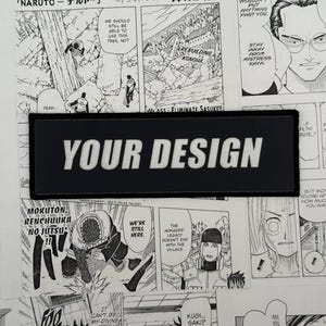 Pode incluir: Um patch retangular preto com as palavras "YOUR DESIGN" em letras brancas e em negrito. O patch está definido contra um fundo de páginas de banda desenhada manga a preto e branco.